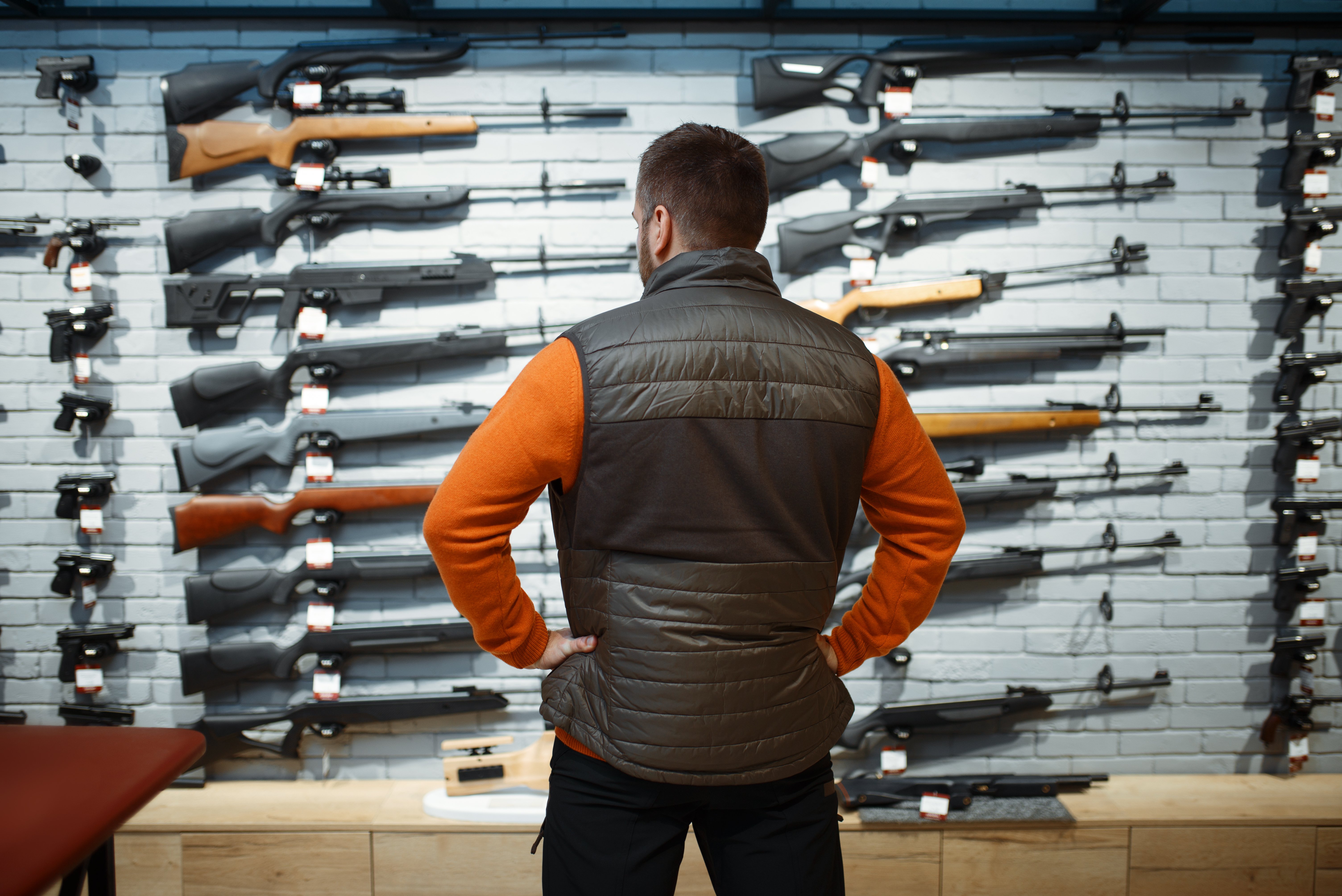 man looking at rifles in a store